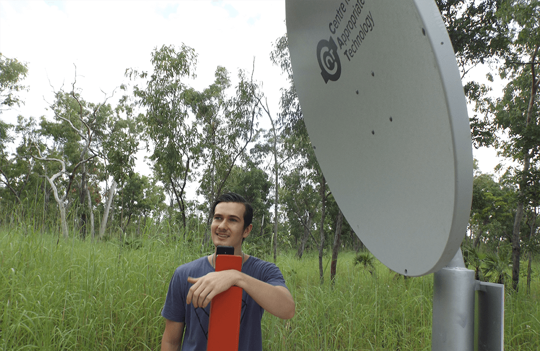 Man standing next to a CfAT satellite dish at South Alligator River in Kakadu National Park.