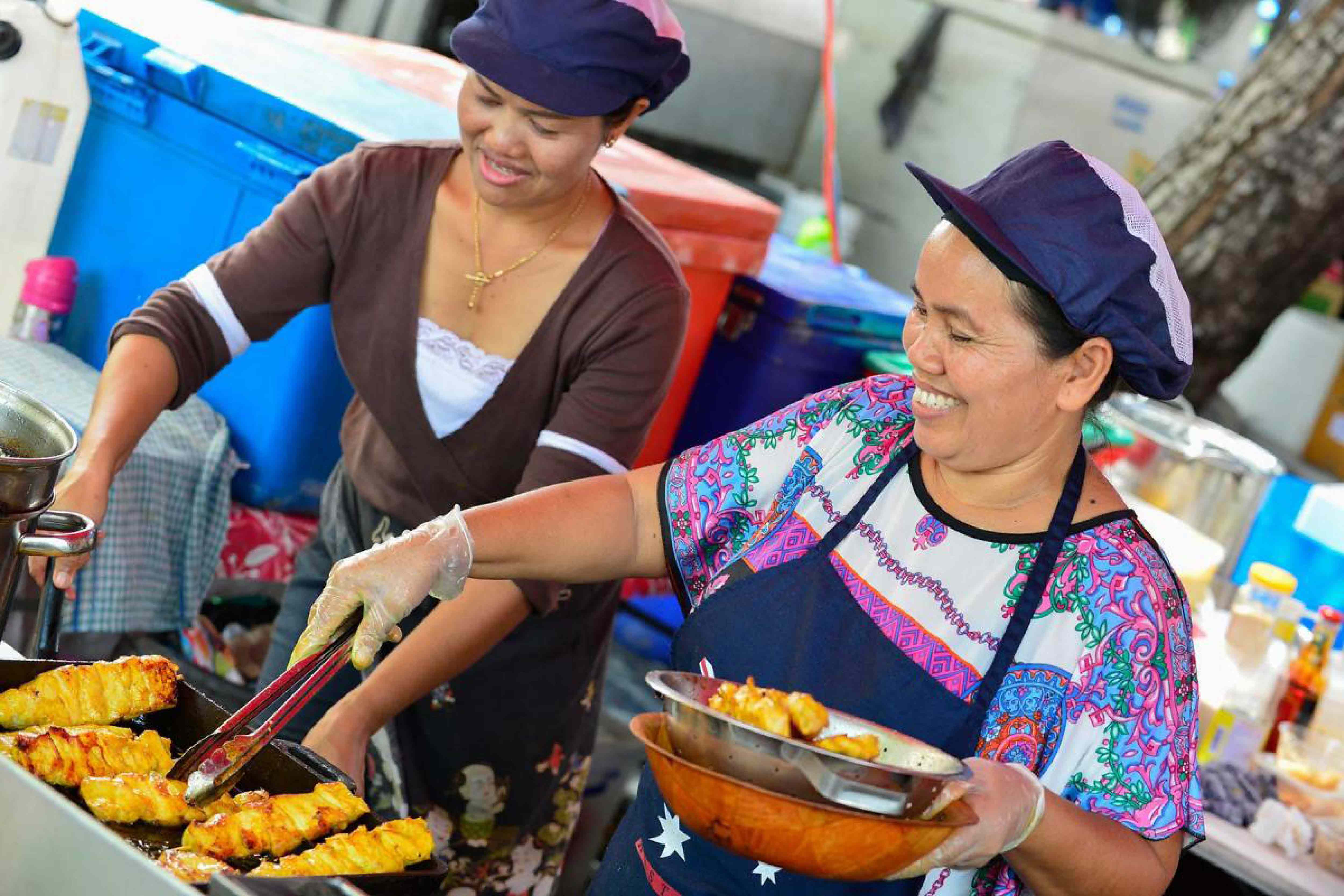 Ladies cooking satays in a market stall